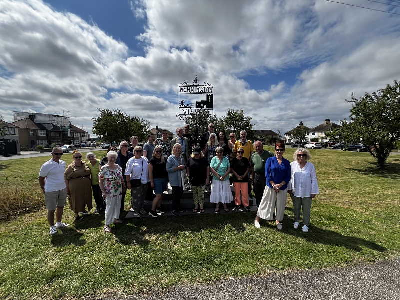 Group photo of Wennington residents next to the Village sign